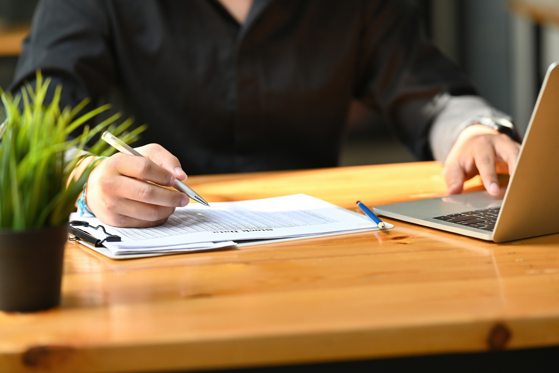 Cropped image of a businessman writing on a paperwork at the wooden table.