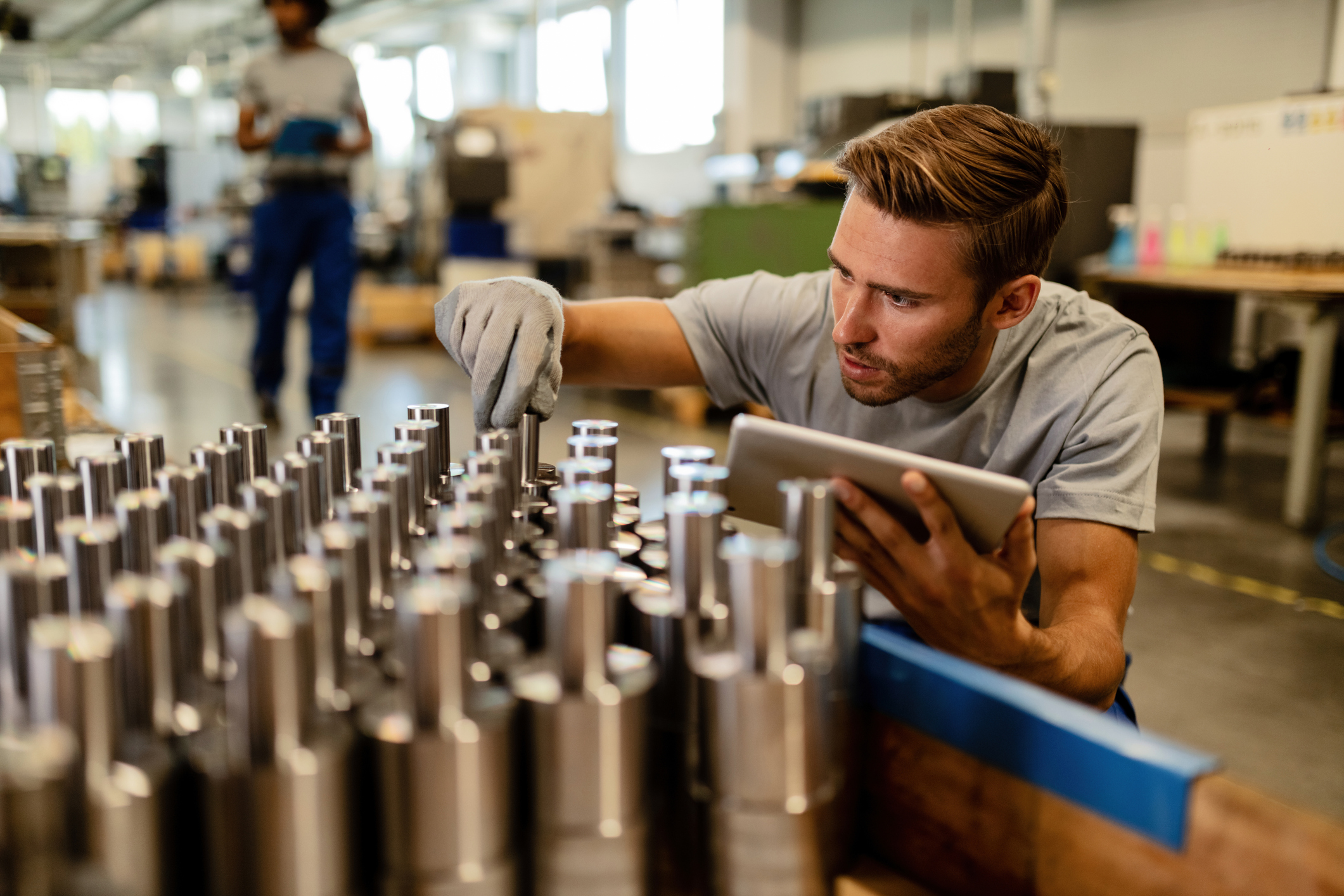 Young steel worker performing quality control of manufactured products in a warehouse.